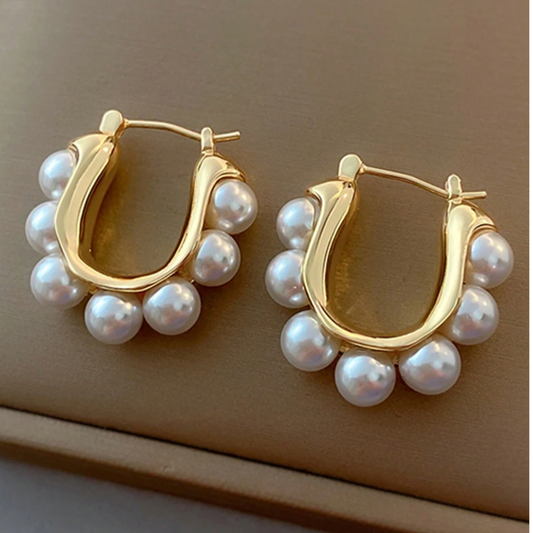 Gold hoop earrings with pearl beads on a beige background