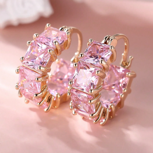 Pink gemstone earrings with gold setting on a soft pink background