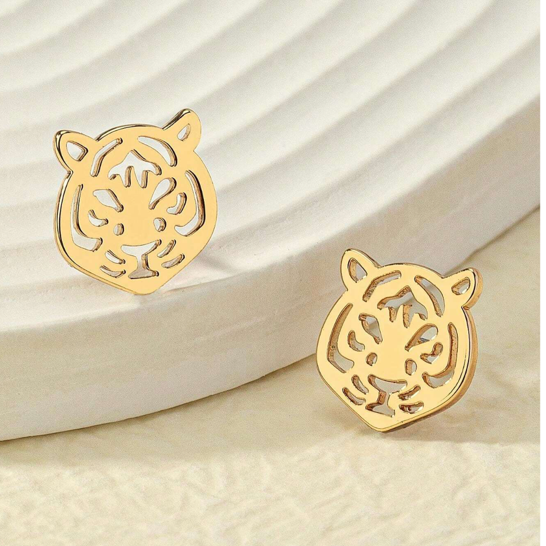 Gold tiger head earrings on a beige background
