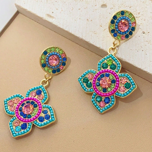 Colorful floral earrings with gemstone-like beads on a beige surface