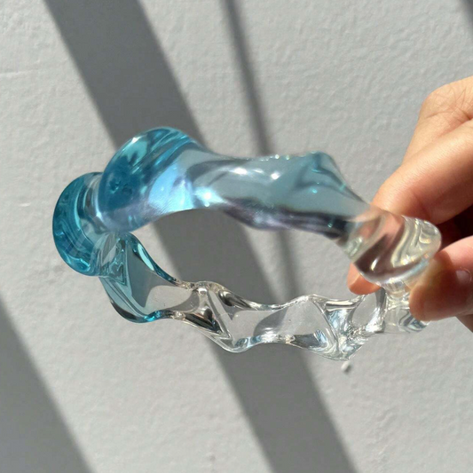 Clear and blue plastic tool held by a hand on a light gray background