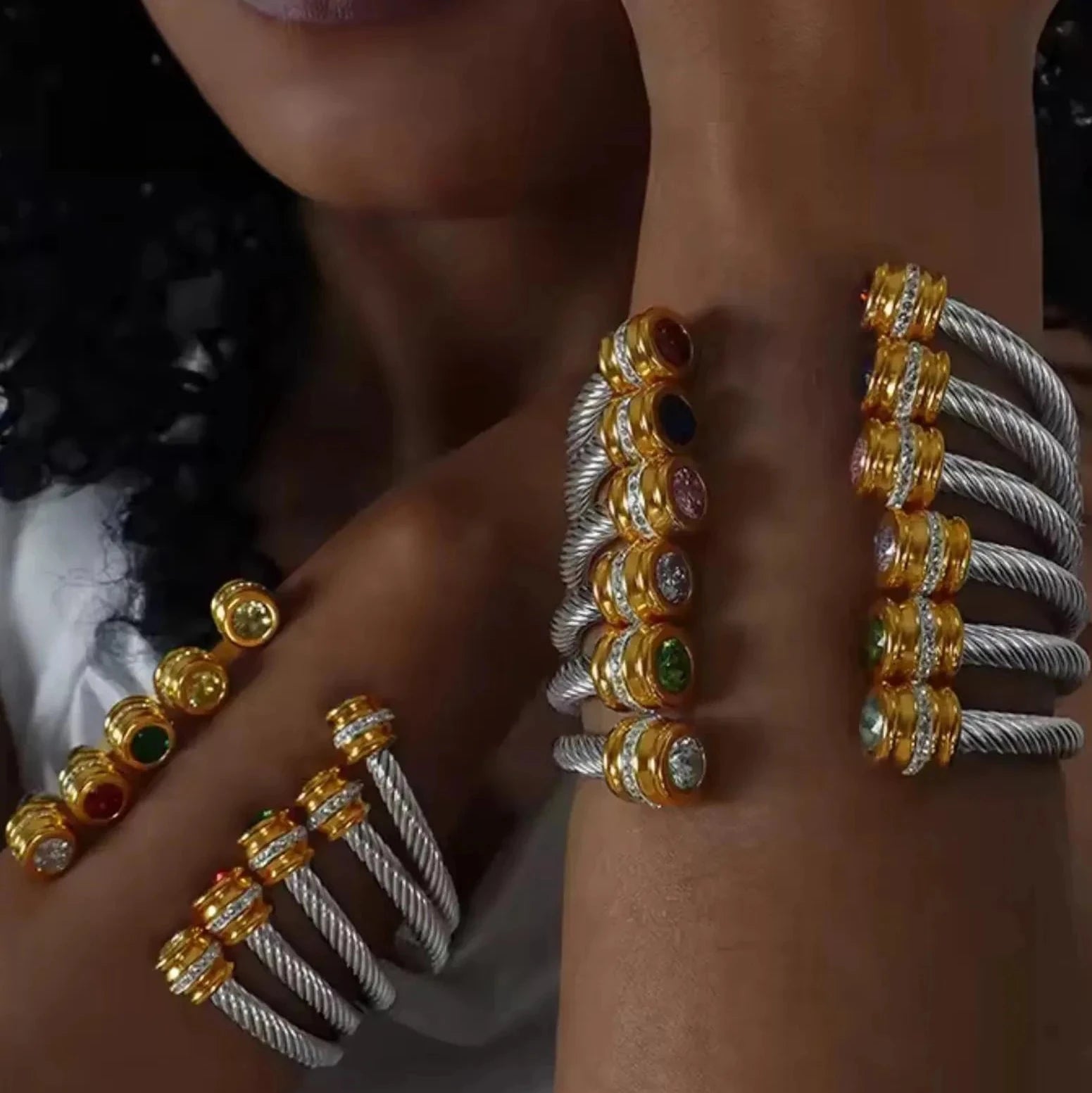 Close-up of a person's wrist wearing multiple gold and silver bracelets with gemstones.